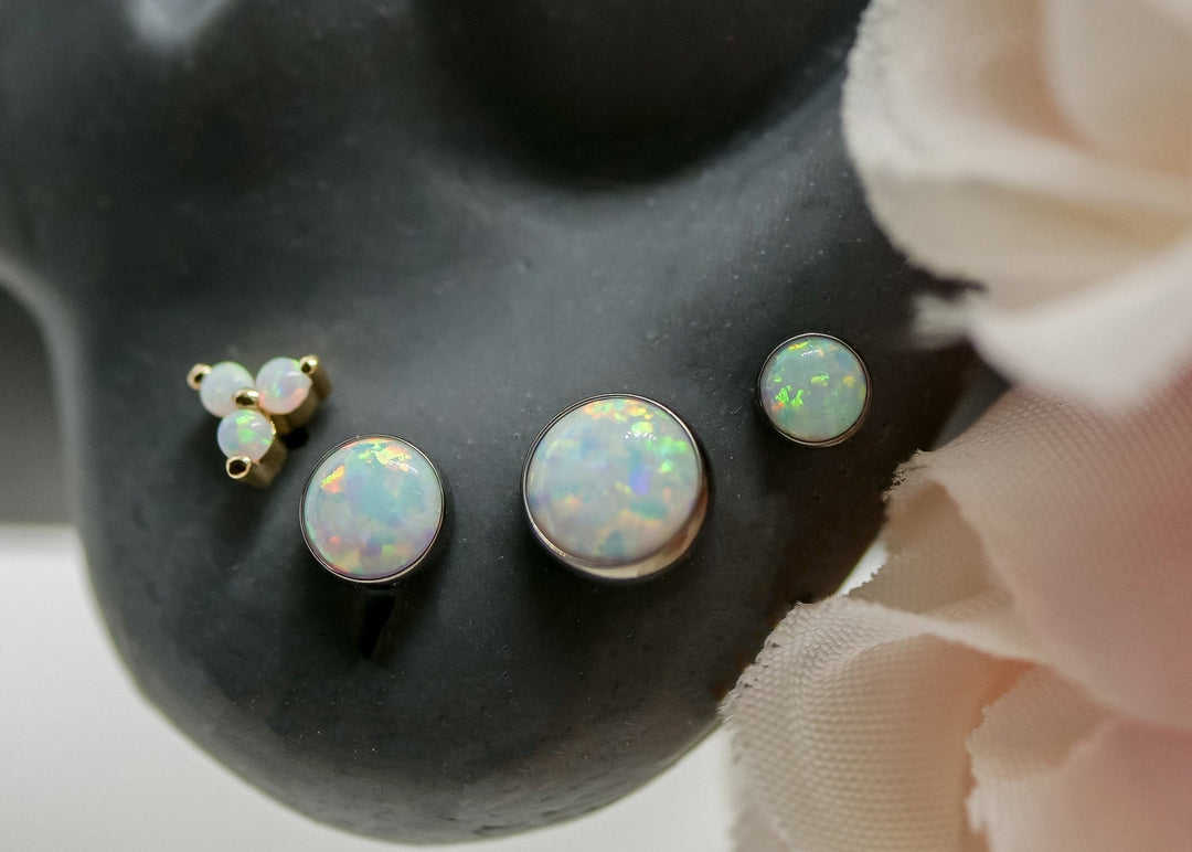 ear lobe piercings with junipurr rose gold white opal trinity, 3 sizes of neometal bezel white opals, and a junipur double millgrain pearshaped end with opal