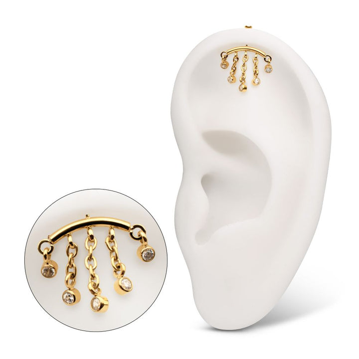 Gold earring with dangling charms on a white ear model and background