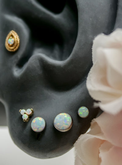 ear lobe piercings with junipurr rose gold white opal trinity, 3 sizes of neometal bezel white opals, and a junipur double millgrain pearshaped end with opal 